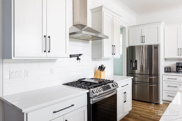 kitchen with wall chimney range hood, tasteful backsplash, dark hardwood / wood-style flooring, appliances with stainless steel finishes, and white cabinetry