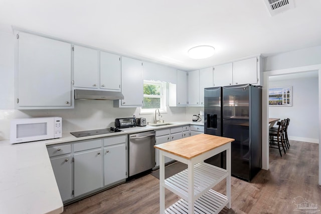 kitchen featuring appliances with stainless steel finishes, gray cabinetry, dark hardwood / wood-style flooring, and sink