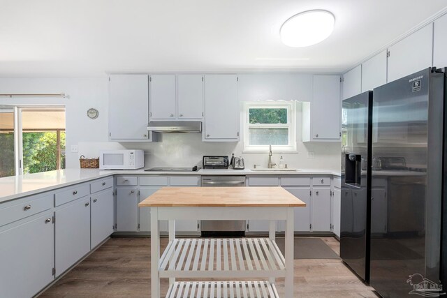 kitchen featuring refrigerator with ice dispenser, black stovetop, light wood-type flooring, and sink