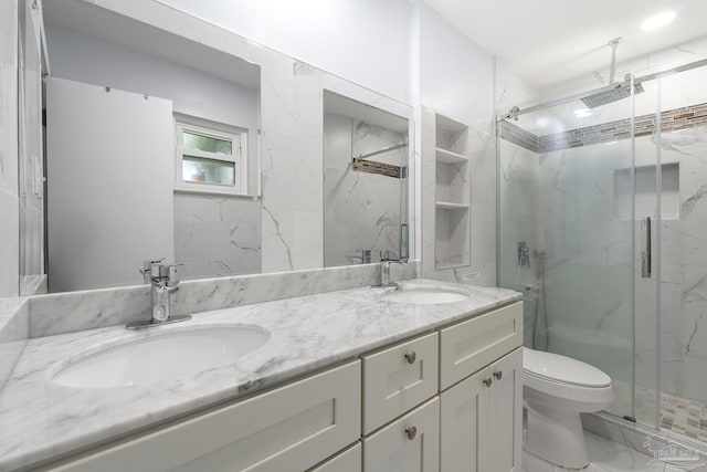 bathroom with a shower with door, vanity, and toilet