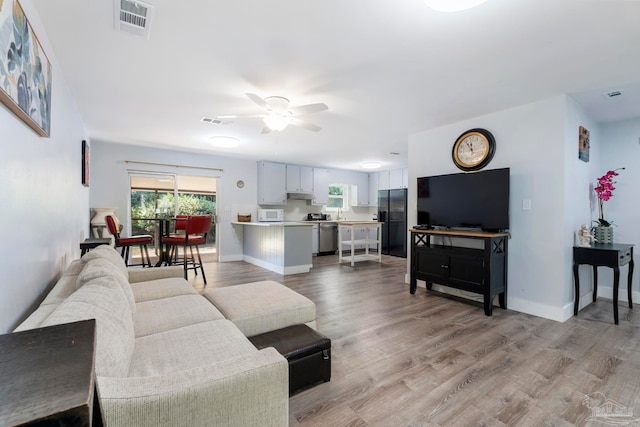 living room with light wood-type flooring and ceiling fan