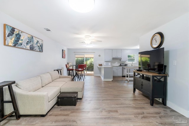 living room with ceiling fan, light hardwood / wood-style flooring, and sink