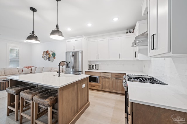 1550 W Romana St, Pensacola, FL 32502 - kitchen featuring appliances with stainless steel finishes, a sink, wall chimney exhaust hood, open floor plan, and tasteful backsplash