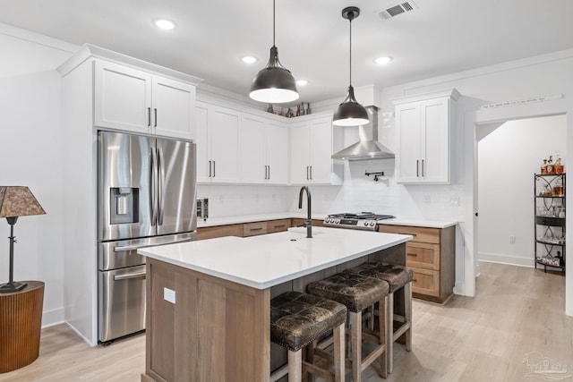 1550 W Romana St, Pensacola, FL 32502 - kitchen with appliances with stainless steel finishes, light wood finished floors, backsplash, wall chimney range hood, and light countertops