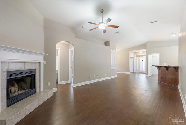 unfurnished living room with ceiling fan, lofted ceiling, dark wood-type flooring, and a tile fireplace