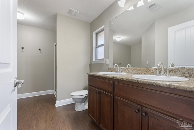 bathroom featuring vanity, a textured ceiling, a shower with door, hardwood / wood-style floors, and toilet