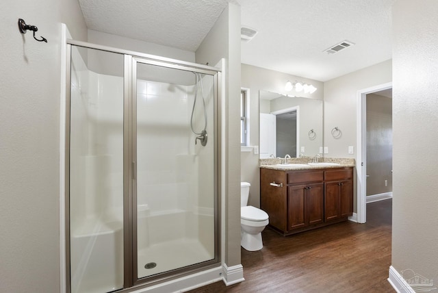 bathroom with hardwood / wood-style floors, a shower with door, a textured ceiling, and toilet