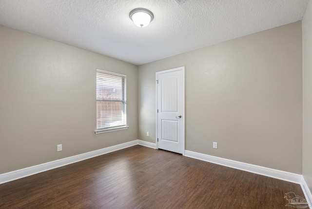 empty room with a textured ceiling and dark hardwood / wood-style floors