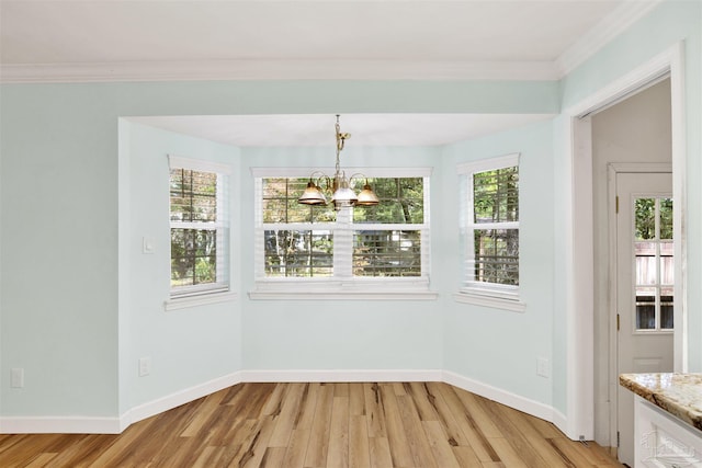 unfurnished dining area with a chandelier, light hardwood / wood-style flooring, and crown molding