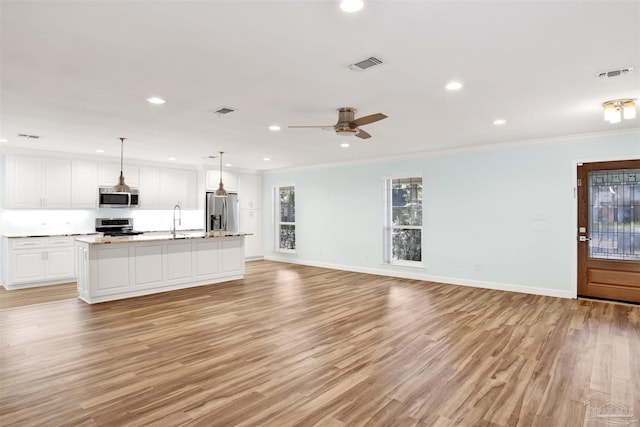 kitchen featuring white cabinets, light hardwood / wood-style flooring, ornamental molding, an island with sink, and appliances with stainless steel finishes