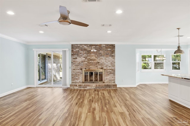 unfurnished living room featuring a fireplace, ornamental molding, light hardwood / wood-style floors, and a healthy amount of sunlight