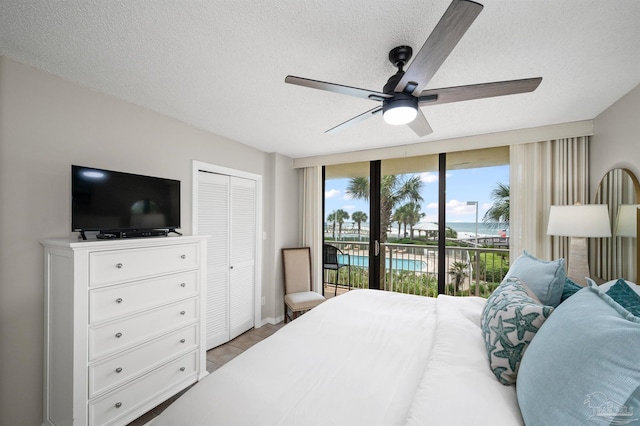 bedroom featuring ceiling fan, a wall of windows, a textured ceiling, access to outside, and a closet