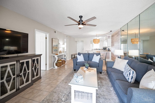 living room featuring ceiling fan, light tile patterned flooring, and a textured ceiling