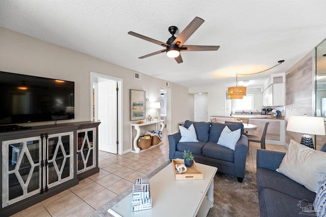 living room featuring ceiling fan, light tile patterned floors, and a textured ceiling