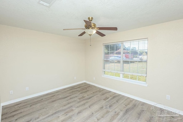 spare room with ceiling fan, light wood-type flooring, and a textured ceiling