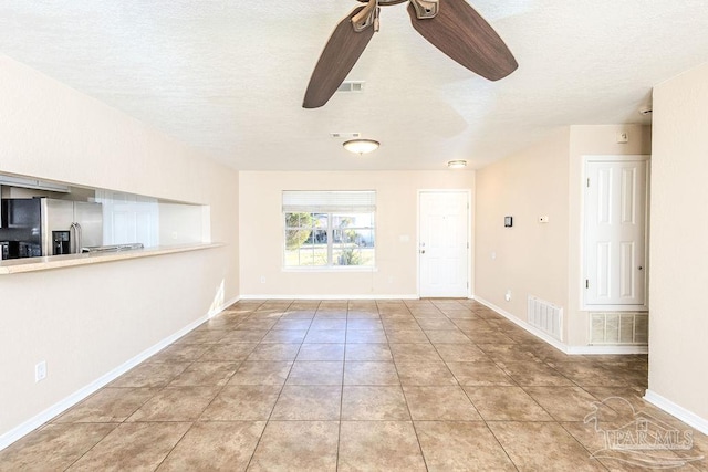 unfurnished living room featuring ceiling fan, light tile patterned flooring, and a textured ceiling