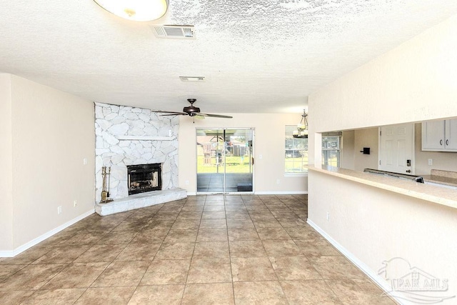 unfurnished living room featuring a fireplace, a textured ceiling, and ceiling fan