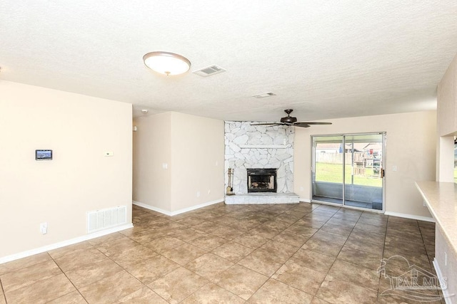 unfurnished living room with tile patterned floors, ceiling fan, a fireplace, and a textured ceiling