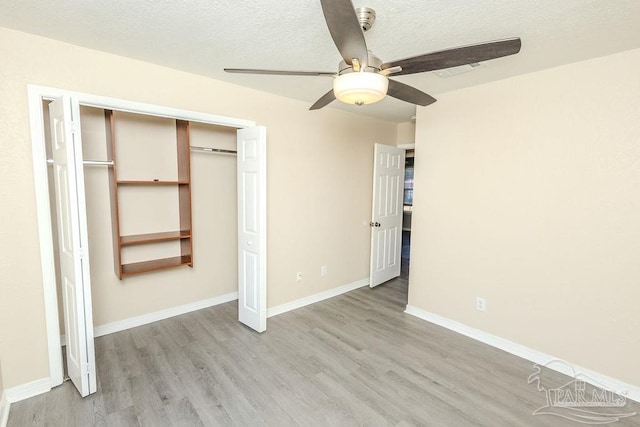 unfurnished bedroom with ceiling fan, a closet, a textured ceiling, and light hardwood / wood-style flooring