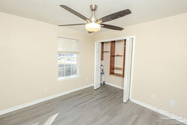 unfurnished bedroom featuring a textured ceiling, light hardwood / wood-style flooring, a closet, and ceiling fan