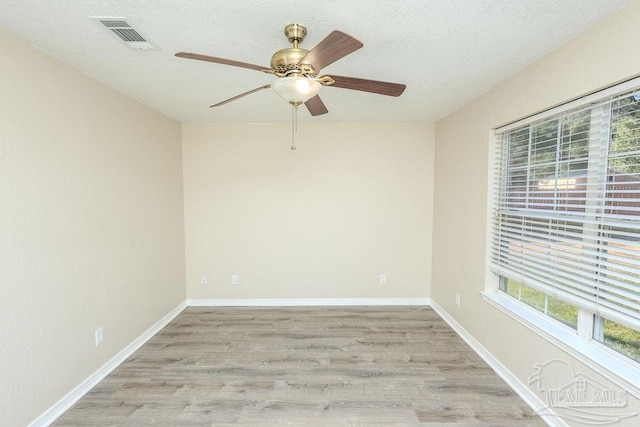 unfurnished room with a textured ceiling and light hardwood / wood-style floors