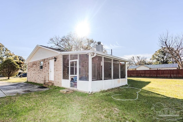 rear view of house with a sunroom and a yard