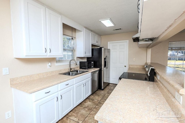 kitchen featuring appliances with stainless steel finishes, white cabinetry, a healthy amount of sunlight, and sink