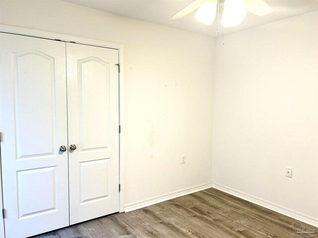 unfurnished bedroom featuring ceiling fan, wood-type flooring, and a closet