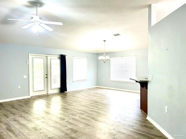 unfurnished living room featuring ceiling fan with notable chandelier, french doors, and hardwood / wood-style flooring