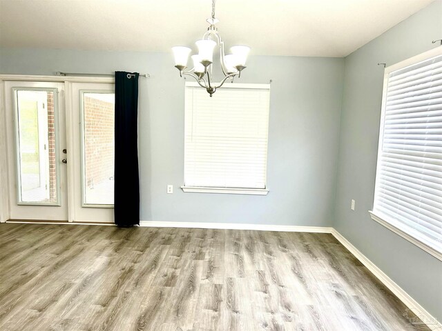 unfurnished dining area with hardwood / wood-style flooring and an inviting chandelier