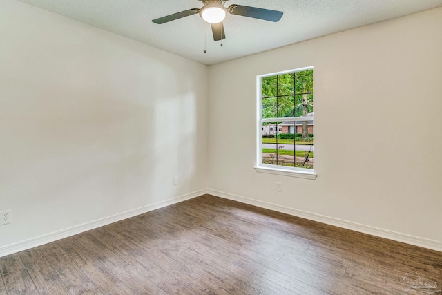 unfurnished room with a wealth of natural light, dark hardwood / wood-style flooring, and ceiling fan