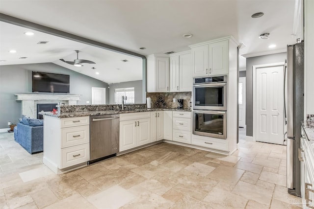 kitchen featuring white cabinets, kitchen peninsula, stainless steel appliances, and dark stone counters