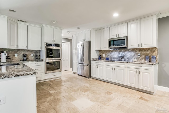 kitchen featuring backsplash, stainless steel appliances, white cabinetry, and stone countertops