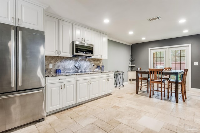 kitchen with tasteful backsplash, white cabinets, stone countertops, and appliances with stainless steel finishes