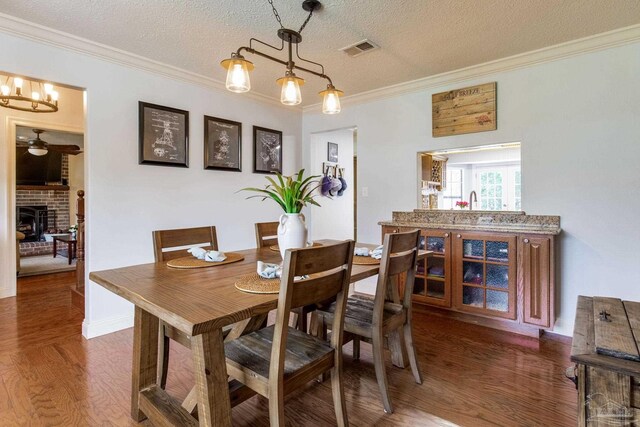 3905 Tiger Point Blvd, Gulf Breeze, FL 32563 - dining space featuring wood finished floors, ornamental molding, a fireplace, a textured ceiling, and ceiling fan