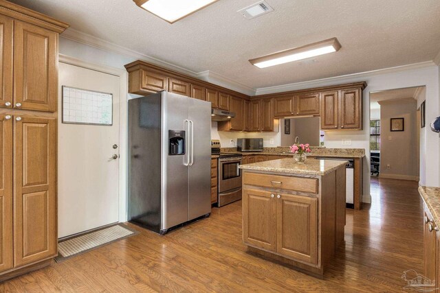 3905 Tiger Point Blvd, Gulf Breeze, FL 32563 - kitchen featuring appliances with stainless steel finishes, under cabinet range hood, a center island, dark wood-type flooring, and ornamental molding