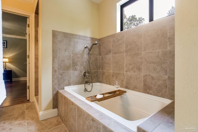 3905 Tiger Point Blvd, Gulf Breeze, FL 32563 - bathroom with a relaxing tiled tub, crown molding, tiled shower, tile patterned flooring, and baseboards