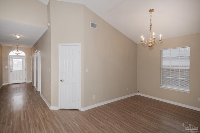 foyer entrance featuring hardwood / wood-style floors, high vaulted ceiling, and a notable chandelier