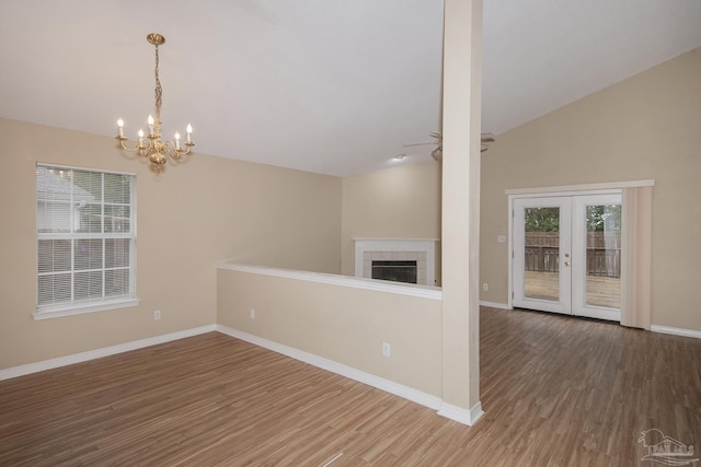 unfurnished living room with plenty of natural light, vaulted ceiling, wood-type flooring, and french doors