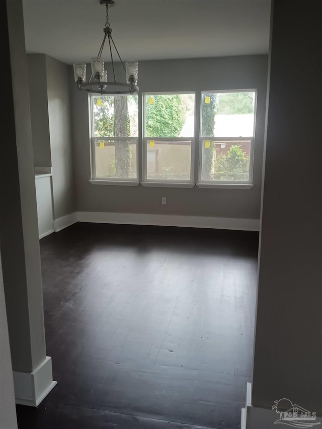 unfurnished room featuring dark wood-type flooring and an inviting chandelier