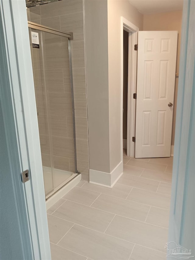 bathroom featuring a shower with shower door and tile patterned flooring