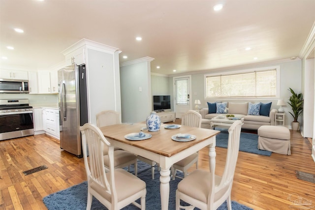 dining area with crown molding and light hardwood / wood-style flooring