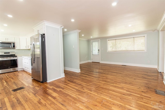 kitchen featuring white cabinetry, ornamental molding, appliances with stainless steel finishes, and light hardwood / wood-style floors