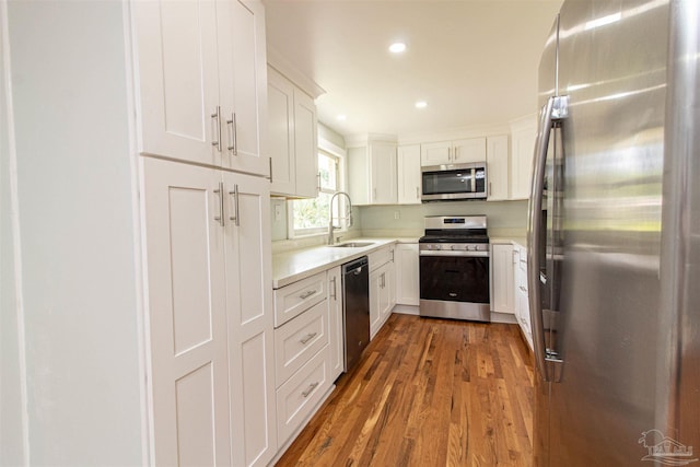 kitchen with stainless steel appliances, sink, dark wood-type flooring, and white cabinets