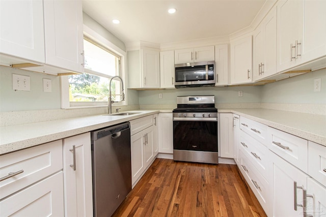 kitchen featuring dark wood-type flooring, sink, light stone counters, appliances with stainless steel finishes, and white cabinets