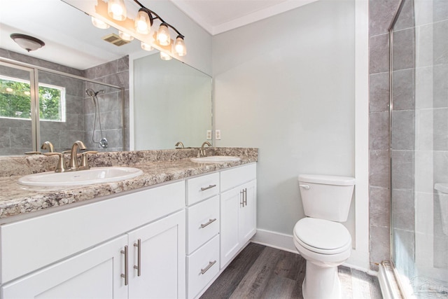 bathroom with toilet, a shower with shower door, wood-type flooring, ornamental molding, and vanity