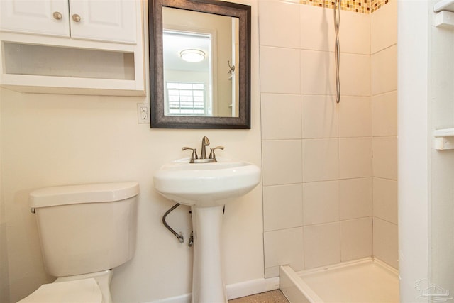 bathroom featuring a tile shower and toilet