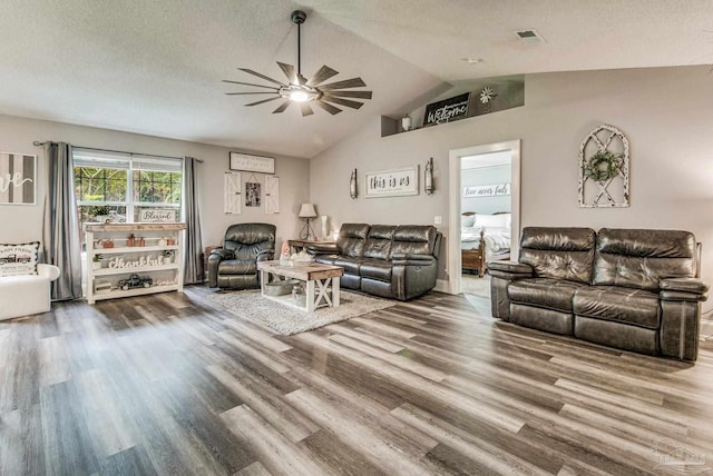 living room with a textured ceiling, hardwood / wood-style flooring, ceiling fan, and vaulted ceiling