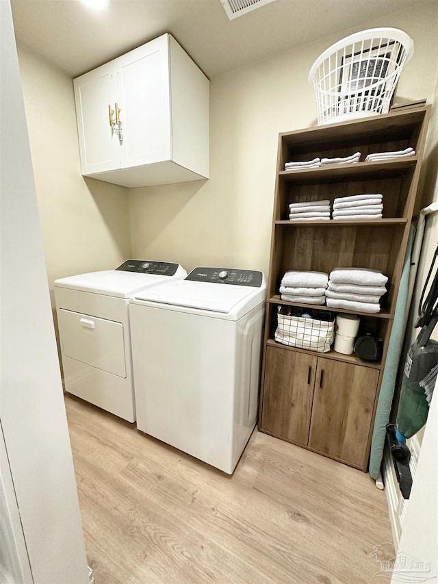 washroom with light wood-style flooring, washer and clothes dryer, and cabinet space