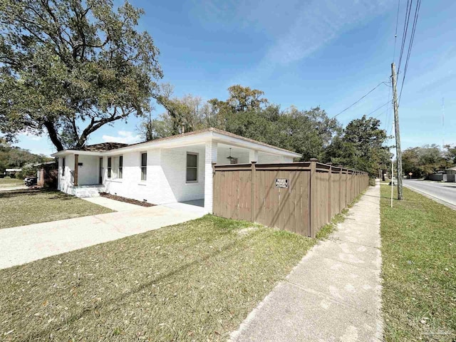 view of side of property featuring driveway, fence, a yard, and a carport